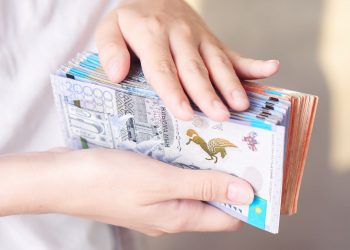 Tenge. A girl in a white t-shirt holding a lot of Kazakh bills close-up.