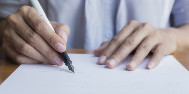 Businessperson Signing Contract,Women writing paper at the desk, man writing with pen and reading books at table,man Signing, Contract, Form. in office ,morning light ,selective focus. 