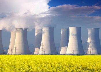 Nuclear power plant with yellow field and big blue clouds.