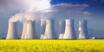 Nuclear power plant with yellow field and big blue clouds.